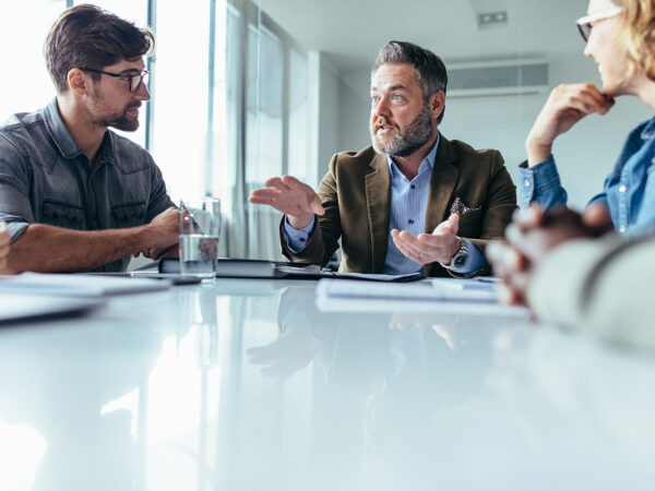 A man controls the conversation during a meeting, illustrating that working with a dominant SME requires pivoting them to focus their expertise.